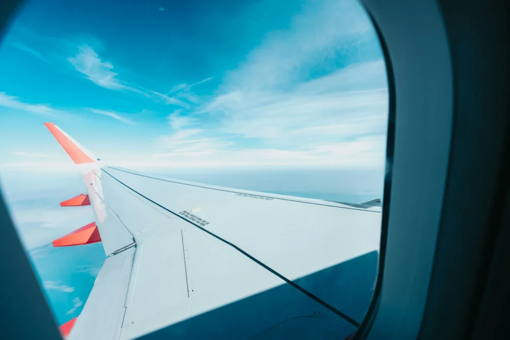 Vista desde la ventanilla de un avión mostrando el ala blanca con detalles rojos sobre un cielo azul claro, simbolizando la elevación de perspectiva y la visión estratégica de True Ventour.